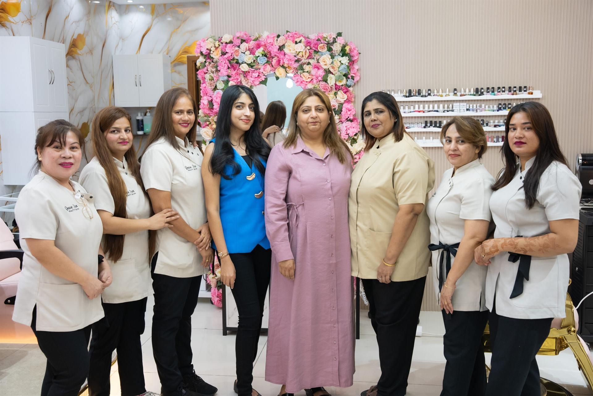 The Grove Star Beauty Salon team in uniform beside the floral arch mirror