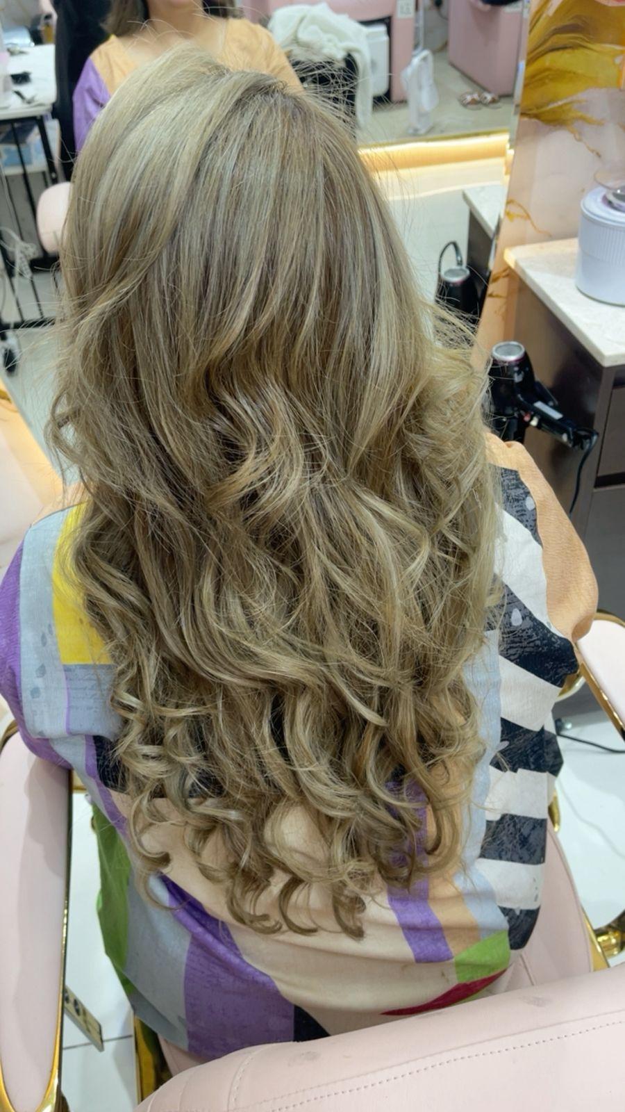 Long layered blonde hair styling with soft curls