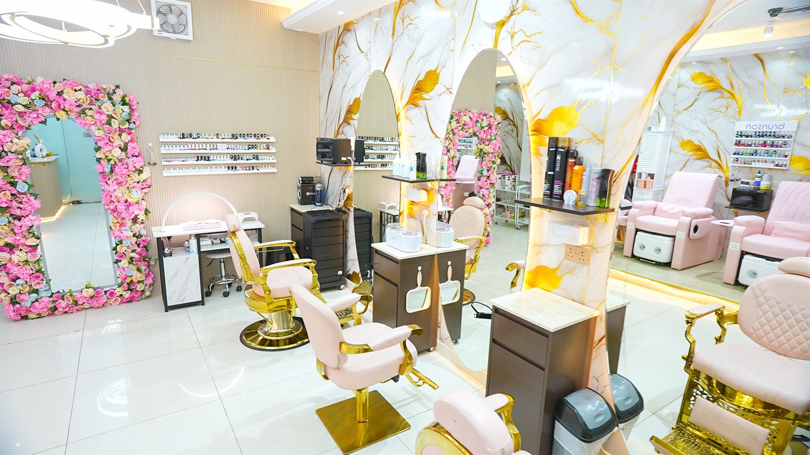 Styling stations with gold chairs, lit mirrors and flower arch